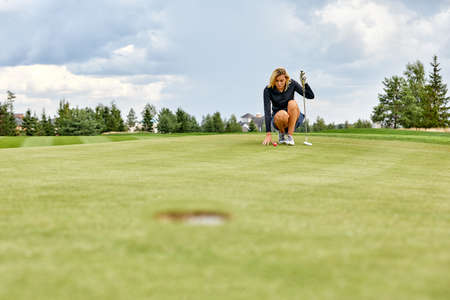 Goal concept, copy space. Women golfing time holding golf equipment on green field background. The pursuit of excellence, personal craftsmanship, royal sport, sports bannerの写真素材