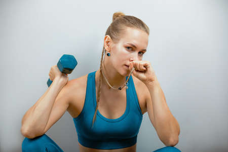 Beautiful fitness model doing exercises with dumbbells in hands on a gray background. Close-up.の写真素材