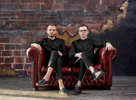 Two successful young businessmen smiling while sitting on a couch. Modern young business. Copy...