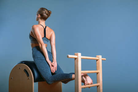 Beautiful positive blond woman is being prepared performing pilates exercise, training on barrel equipment. Fitness concept, special fitness equipment, healthy lifestyle, plastic. Copy space, sport banner for advertisingの写真素材