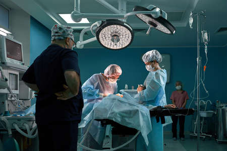Group of surgeons in operating theater. Medical team performing surgery in operation roomの写真素材