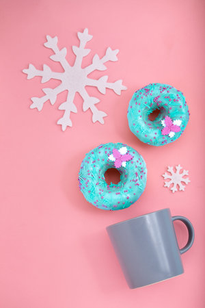 Blue Donuts with icing and coffe cup on pastel rose background. Sweet donuts. Flat lay