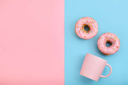 Sweet donuts pink and blue with a mug of coffee. Blue and pink background, game of colors, color conflict. Mock up for design. Copy spaceの写真素材