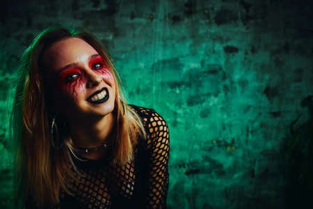 Female model in halloween outfit posing with on a red background. Gorgeous girl in clothes celebrates the day of the dead. Halloween concept, witch costume, bright colors, steam punk.の写真素材
