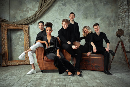 Group of mixed race young people looking at camera while sitting in a beautiful loft. Copy space,...