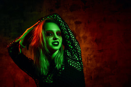 Female model in halloween outfit posing with on a red background. Gorgeous girl in clothes celebrates the day of the dead. Halloween concept, witch costume, bright colors, steam punk.の写真素材