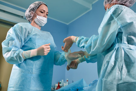 A team of surgeons is preparing for surgery. Surgeons wear sterile clothing before surgery with the...