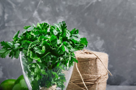 Green fresh bunch of parsley in a glass with water on a gray background. Greens rich in minerals and trace elements healthyの写真素材