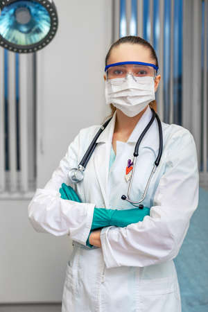 Personal protective equipment, woman doctor in personal protective equipment on the background of a hospital ward. Copy space.の写真素材