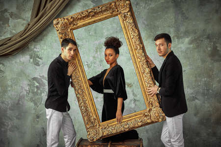 Friends concept, international friends posing on camera with baguette frame from the picture. gray background, copy spaceの写真素材