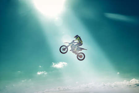 Extreme concept, challenge yourself. Extreme jump on a motorcycle on a background of blue sky with clouds. Copy space, all or nothing.の写真素材