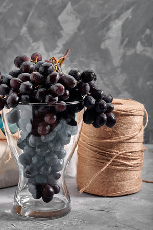 Bunches of fresh ripe red grapes on a concrete textural surface. Branch of pink grapes. Red wine...