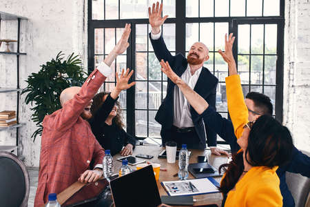Group of joyful smiling happy people celebrate win with arms up. High five friendship deal achievement strike bargain good news friendly consent successful effective strategyの写真素材