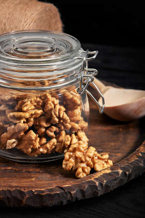 Walnut kernels in a glass bowl on a dark wooden background. Close-up.の写真素材