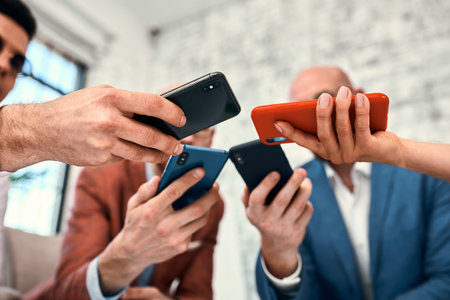 Male and female diverse hands holding cell phones, multiracial business people using smartphones...