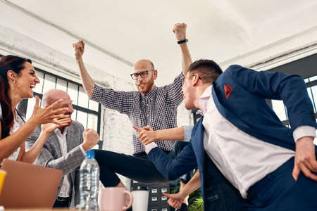 Excited diverse business team employees screaming celebrating good news business win corporate success, happy multi-ethnic colleagues workers group feeling motivated ecstatic about great achievementの写真素材