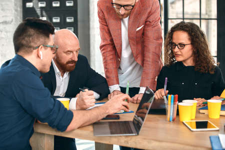 Beautiful business people are using gadgets, talking and smiling during the conference in office. Selective focusの写真素材