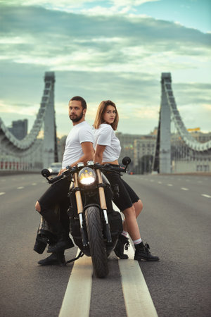Love and romantic concept. Beautiful couple on motorcycle stands opposite each other in the middle...
