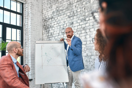 Confident businessman writing on flip charts presentation new project in boardroom at company...