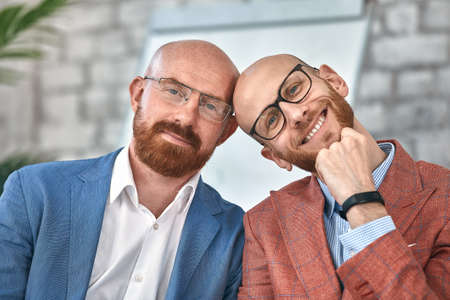 Two smiling businessmen looking at camera. Cheerful young men wearing formal wear posing in office. Business conceptの写真素材