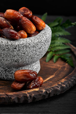 Bowl of dried dates on dark wooden background