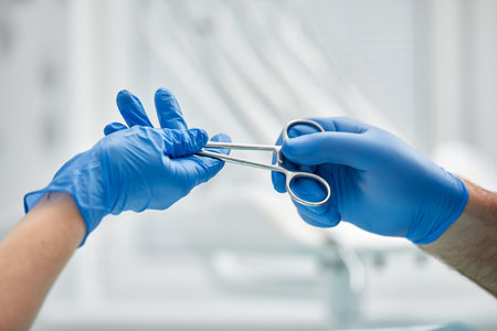 Close-up of the hands of a dentist and nurse surgeon over an operating room during a dental implant...