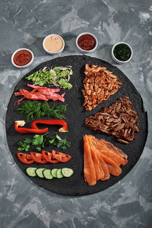 Homemade shawarma, burrito, chicken and salmon roll with vegetables and sauce. Top view ingredients with clear space.の写真素材