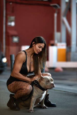 woman with an athletic figure with two dogs american bully on the city streetsの写真素材