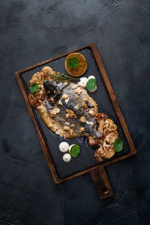 Fish dishes cooking preparation with dorado in backing form in shape of fish with healthy vegetables on dark rustic background with ingredients, top view. Seafood concept.の写真素材