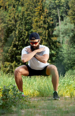 Bearded athletic man doing workout exercise in the outdoor gym in sunsetの写真素材