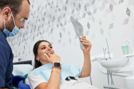 people, medicine, stomatology and health care concept - happy male dentist with woman patient at dental clinic officeの写真素材