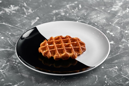 Belgian or american waffle, delicious sweet dish, dessert snack menu concept on black and white plate. top view. copy space for textの写真素材