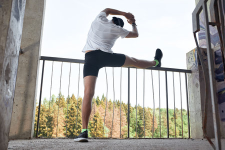 Concentrated male athlete running up stairs to make training more intensive. Sporty handsome young man training alone outdoors. Staircase workout conceptの写真素材