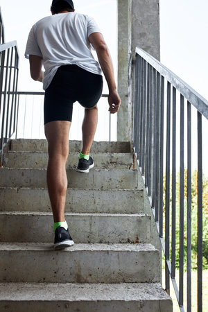 Concentrated male athlete running up stairs to make training more intensive. Sporty handsome young...