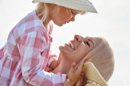 happy mother holding baby smiling on a wheat field in sunlightの写真素材