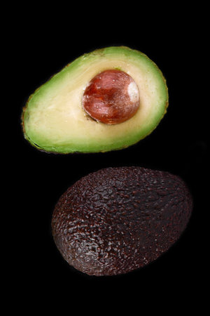 Macro shot of fresh avocados cut in a half on the black backgroundの写真素材