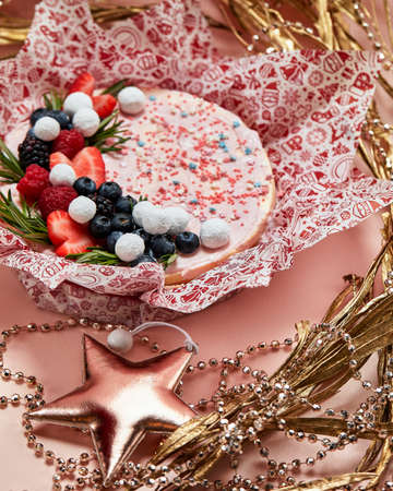 Cake with whipped pink cream, fresh strawberries, blueberries, blackberry and raspberry on pink background. Picture for a menu or a confectionery catalog.の写真素材