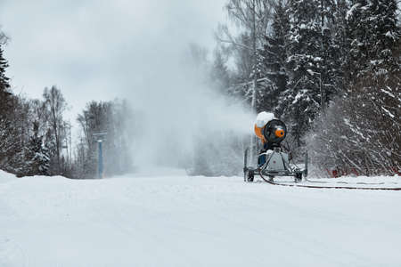 Snow cannon spraying out a fresh dusting of snow on the ski slopes.の写真素材