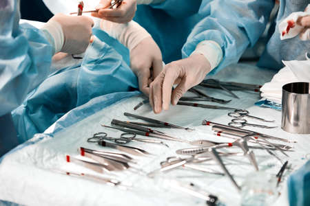 Hands of a team of surgeons close-up in the operating room during the operation, sterile instruments are laid out on the table in the operating room.の写真素材
