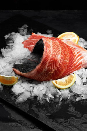 Lightly salted trout. Fresh fish fillet with culinary ingredients, herbs and lemon on a black...