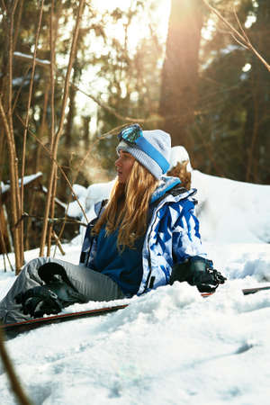 Beautiful young girl in a blue ski suit and helmet. On the head are glasses for snowboarding. Snow-covered mountain landscape. Portrait of a rider. Thats what happiness looks like.の写真素材