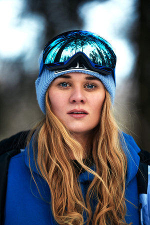 Beautiful young girl in a blue ski suit and helmet. On the head are glasses for snowboarding. Snow-covered mountain landscape. Portrait of a rider. Thats what happiness looks like.の写真素材