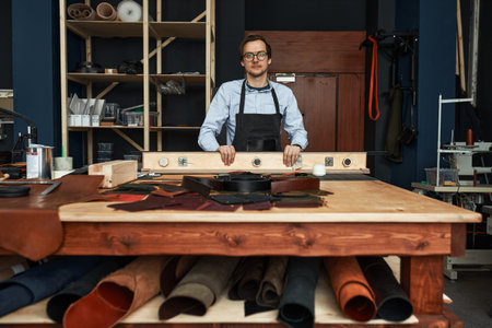Skilled leather manufacture worker cutting some samples in workshop studioの写真素材