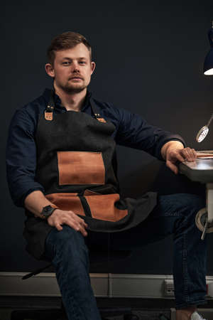 Working process of leather craftsman. Tanner or skinner sews leather on a special sewing machine, close up.worker sewing on the sewing machineの写真素材