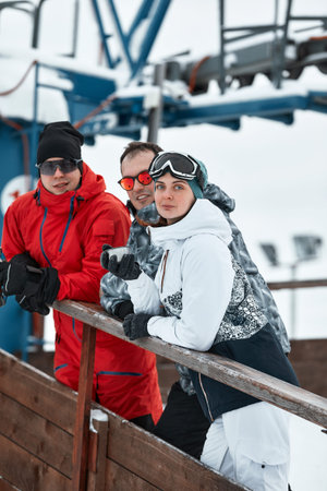 group of skiers friends on the mountain are resting and drinking coffee from a thermos on the...
