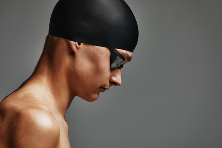 Face of a man swimmer close-up, gray background, copy space, young guy swimmer in a mask and swimming capの写真素材
