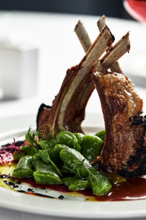 Grilled rack of lamb, close-up. Lamb bone medallions from the chef, tender lamb meat on a light plate with garnishの写真素材