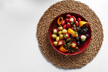 Pickled vegetables in a plate, olives, olives, stuffed peppers, radishes. Assorted vegetables, vegetables with spices in oil close-up on a white background, top view, copyspaceの写真素材