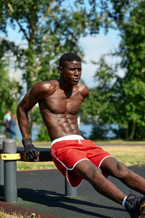 Athlete doing push-ups on the sports ground, African American athlete doing push-ups on outdoor gym...