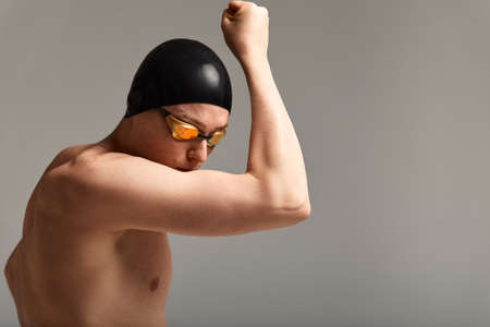 A swimmer kisses his hands before the swim, against a gray background.の写真素材